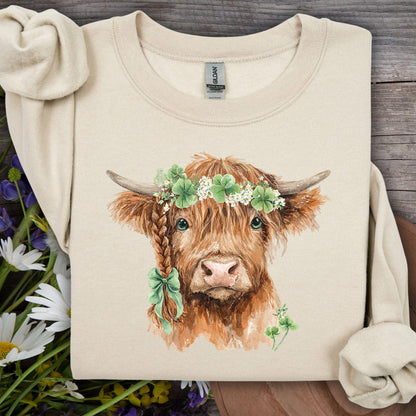 Sand sweatshirt with watercolor Highland cow, clover crown, and braided hair with green bow.