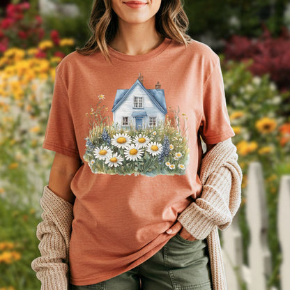 Garment-dyed t-shirt with a blue cottage and wildflower field design, worn by a woman with a cardigan.