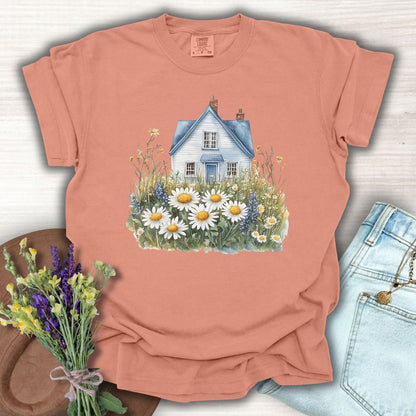 Terracotta garment-dyed cotton t-shirt with a blue cottage and wildflower field design.