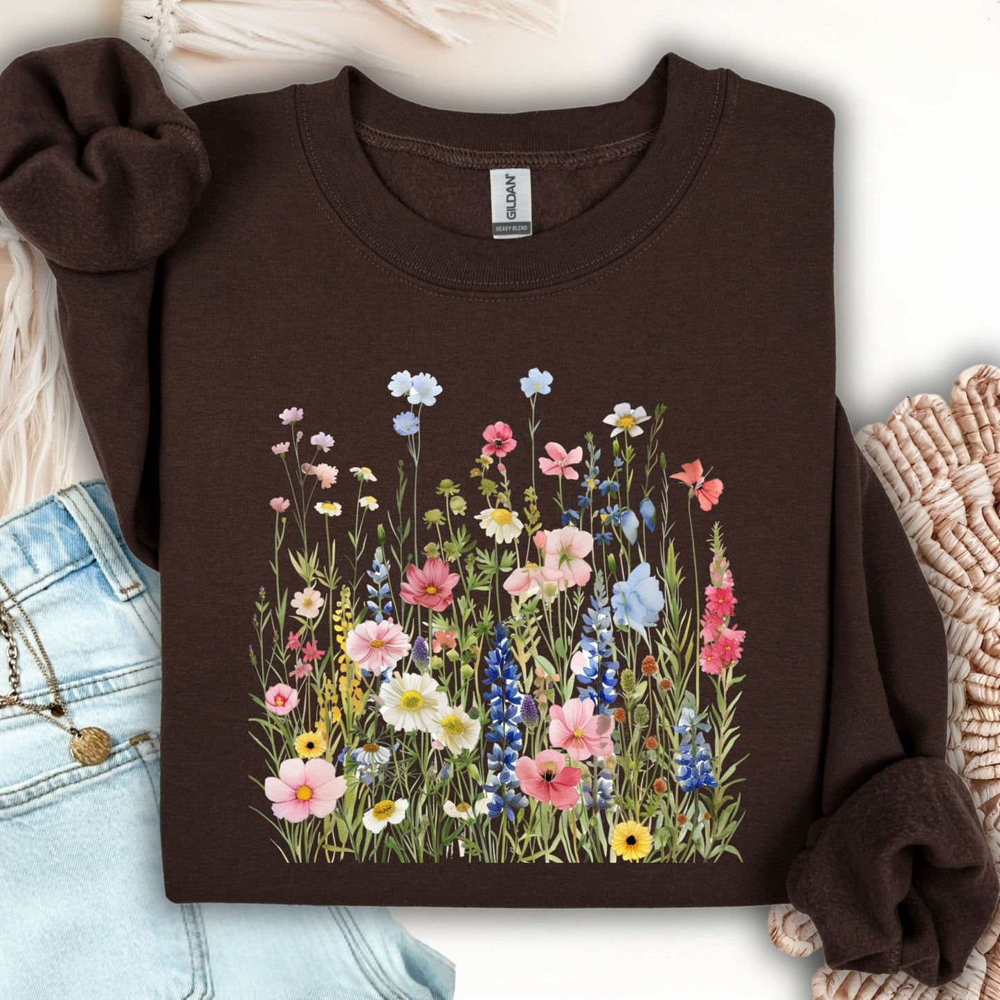 Dark Chocolate Summer Meadow sweatshirt with watercolor wildflowers, folded on a white surface with jeans.