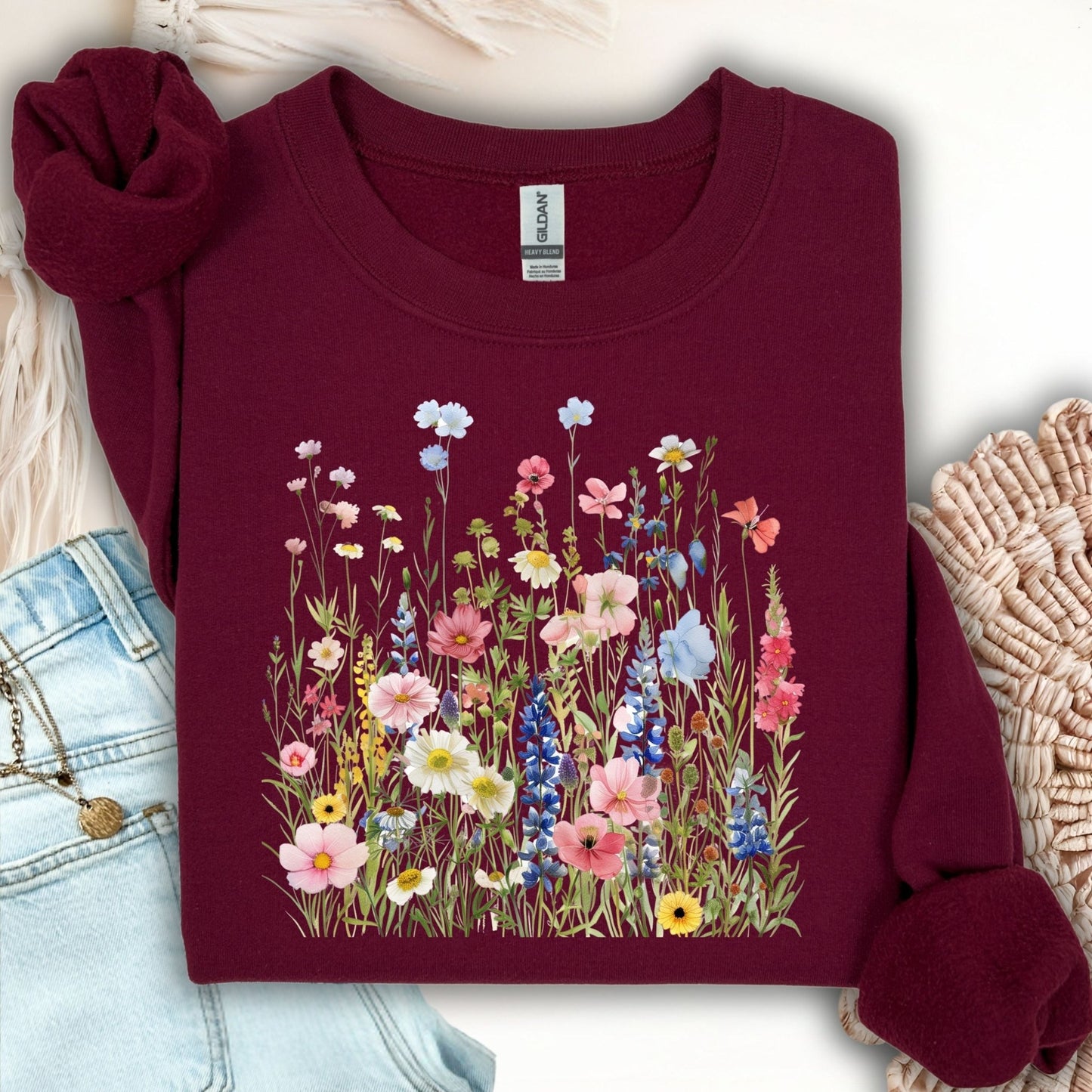 Maroon Summer Meadow sweatshirt with watercolor wildflowers, shown with jeans and a necklace.