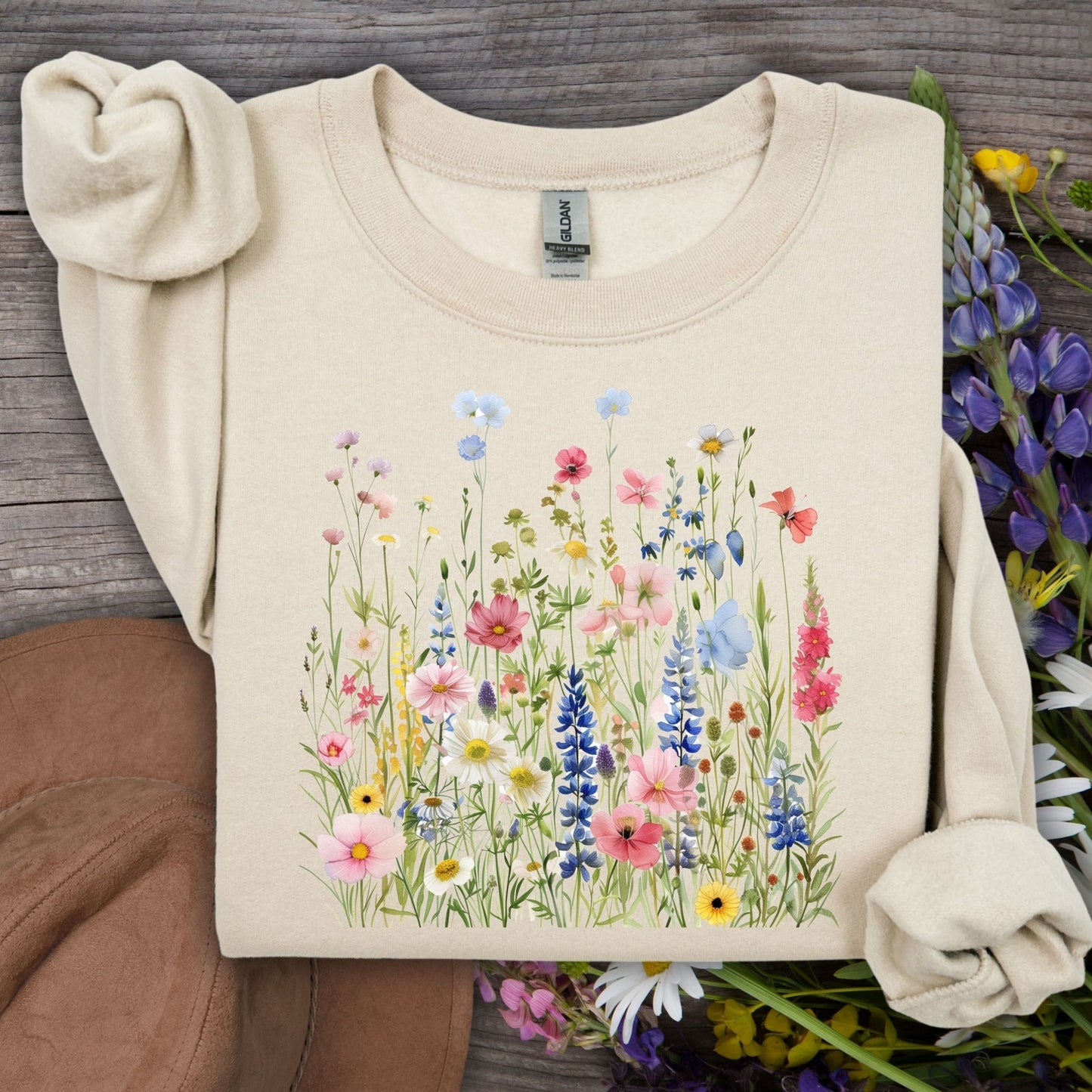 Sand Summer Meadow sweatshirt with watercolor wildflowers on a rustic wooden background.