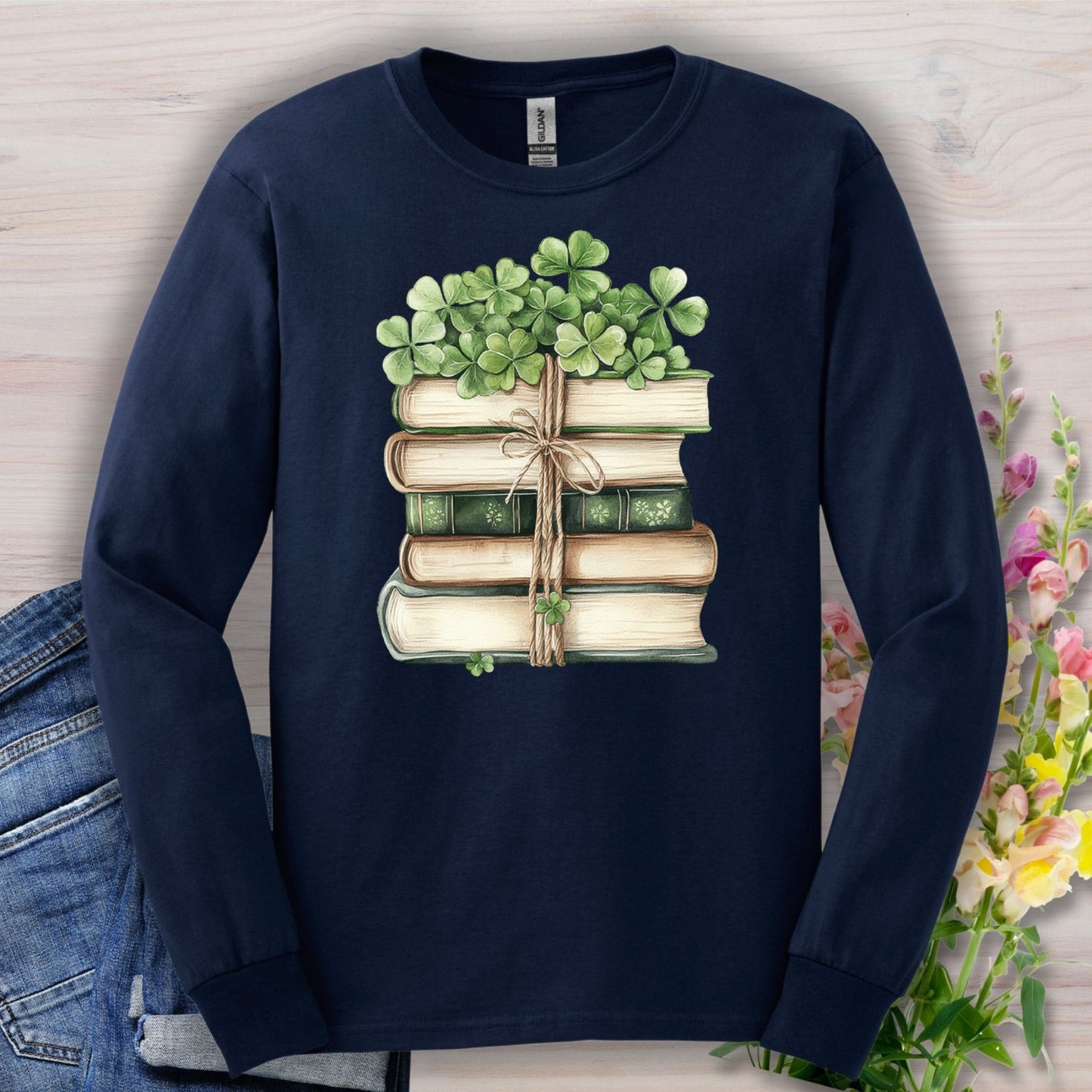 Navy long sleeve tee with a watercolor stack of vintage books tied with twine and clovers.