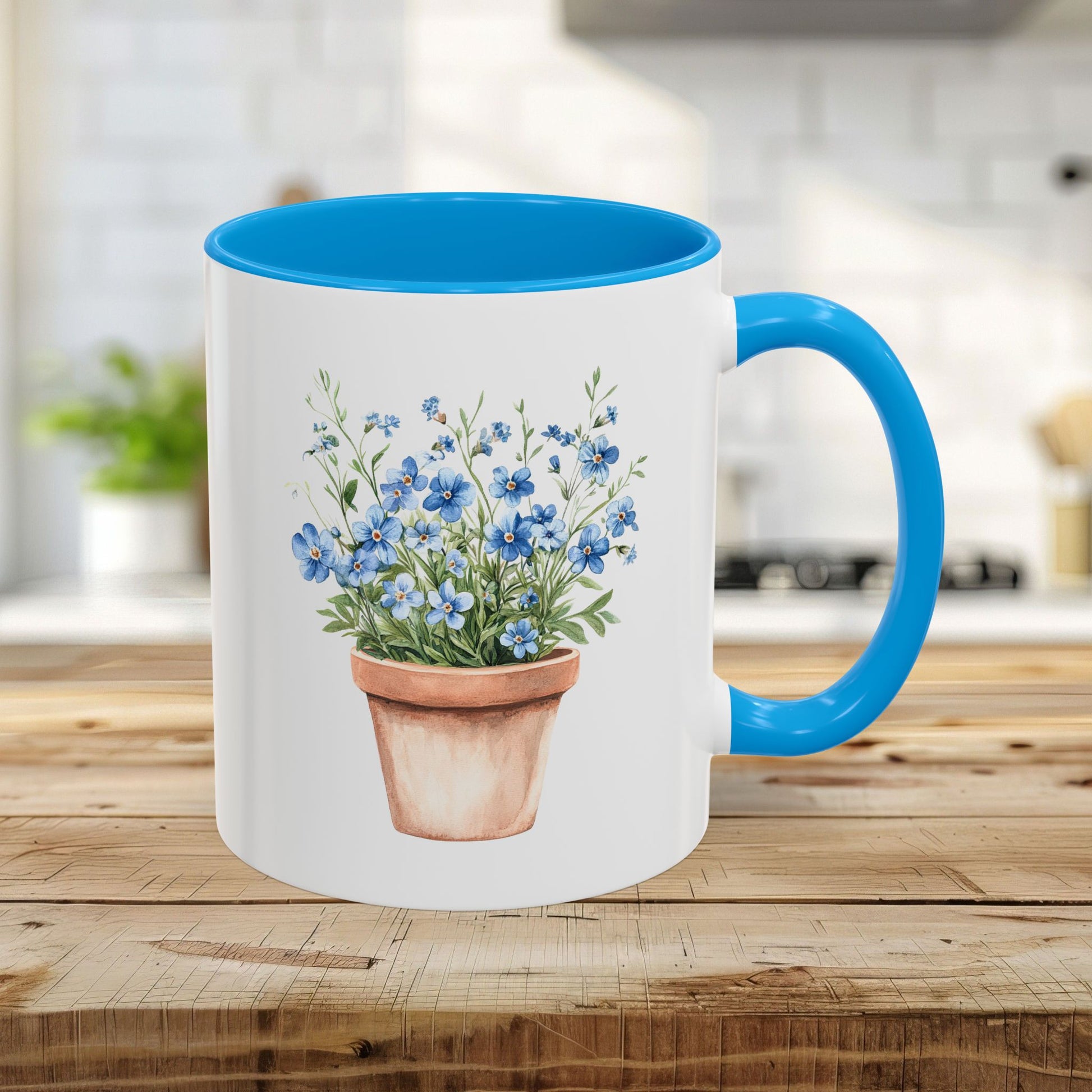 White ceramic mug with light blue handle/interior, featuring a watercolor terracotta pot with blue forget-me-nots.