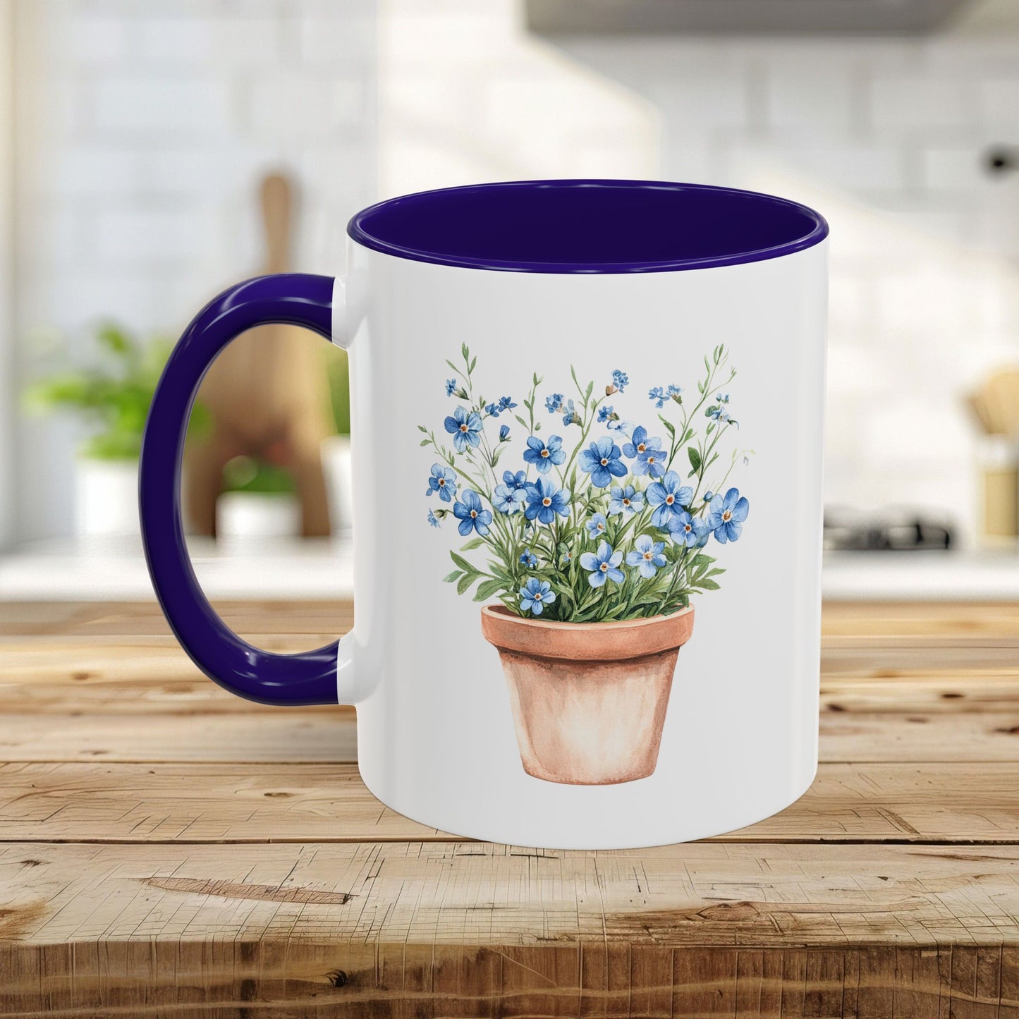 White ceramic mug with blue handle/interior, featuring a watercolor terracotta pot with blue forget-me-nots.