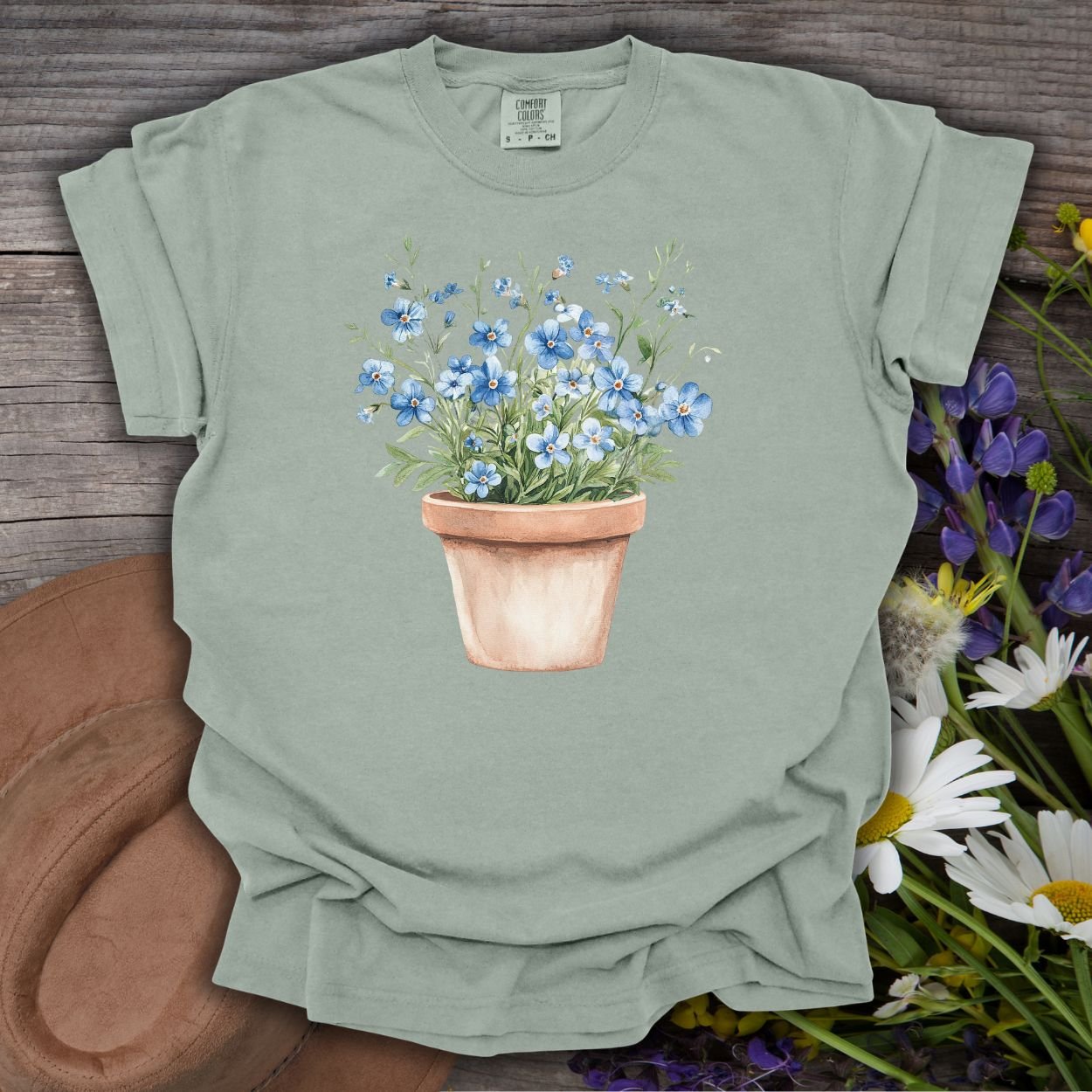 Garment-dyed Bay green cotton t-shirt with a watercolor terracotta pot of blue forget-me-nots.