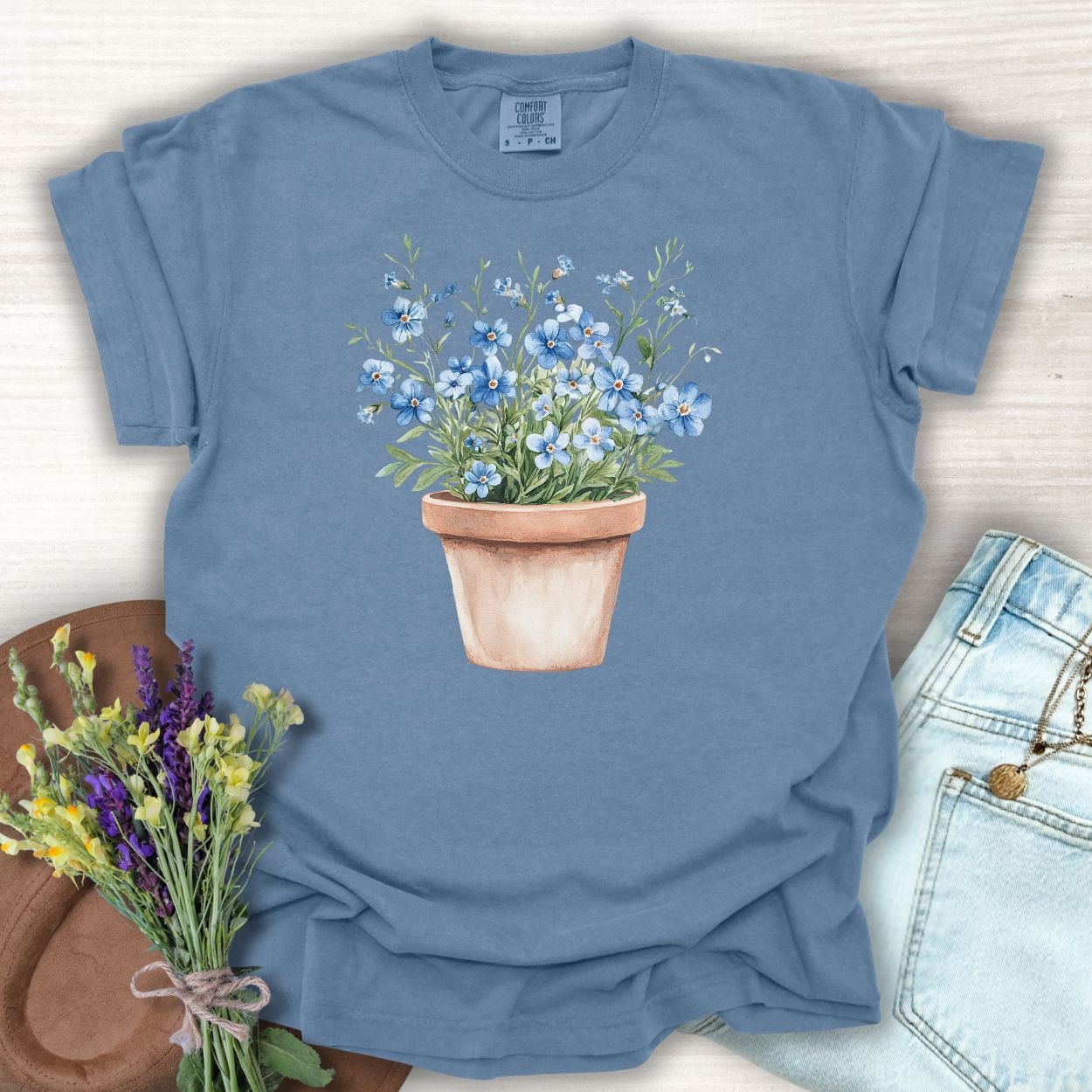 Blue Jean S t-shirt with a watercolor terracotta pot of blue forget-me-nots.