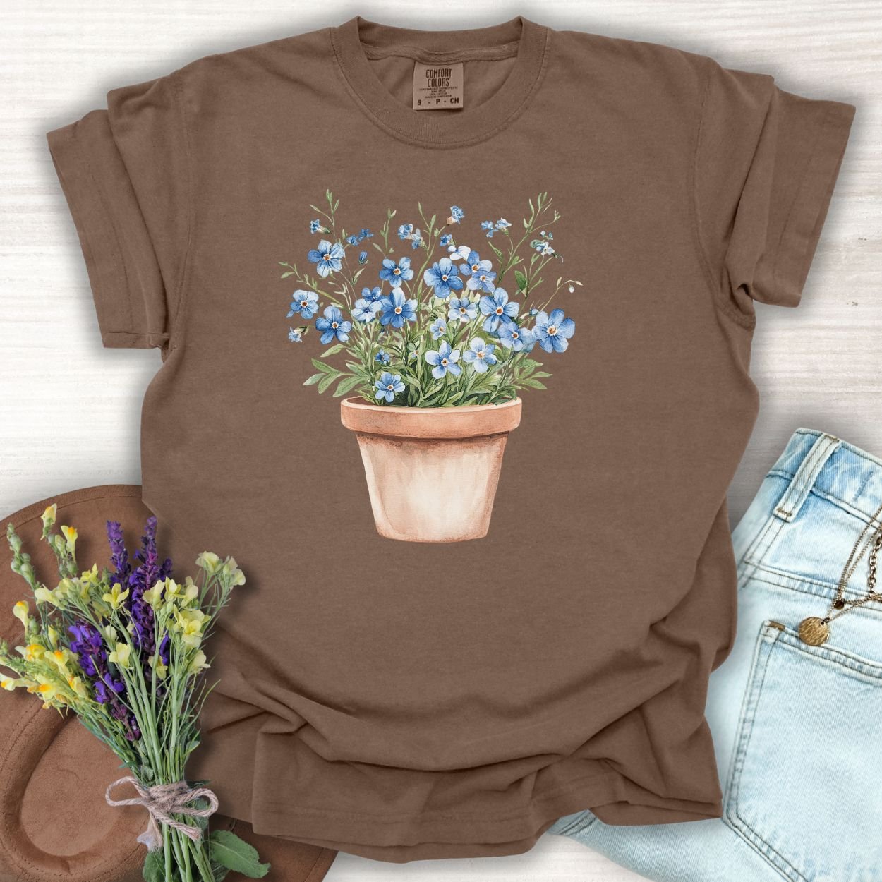 Espresso brown cotton t-shirt with a watercolor terracotta pot of blue forget-me-nots.