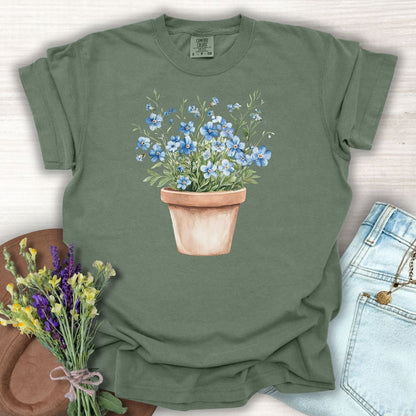 Moss green relaxed-fit t-shirt with a watercolor terracotta pot of blue forget-me-nots.