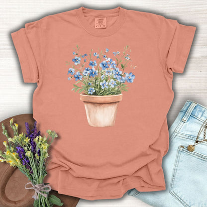 Terracotta S-size t-shirt with a watercolor pot of blue forget-me-nots.