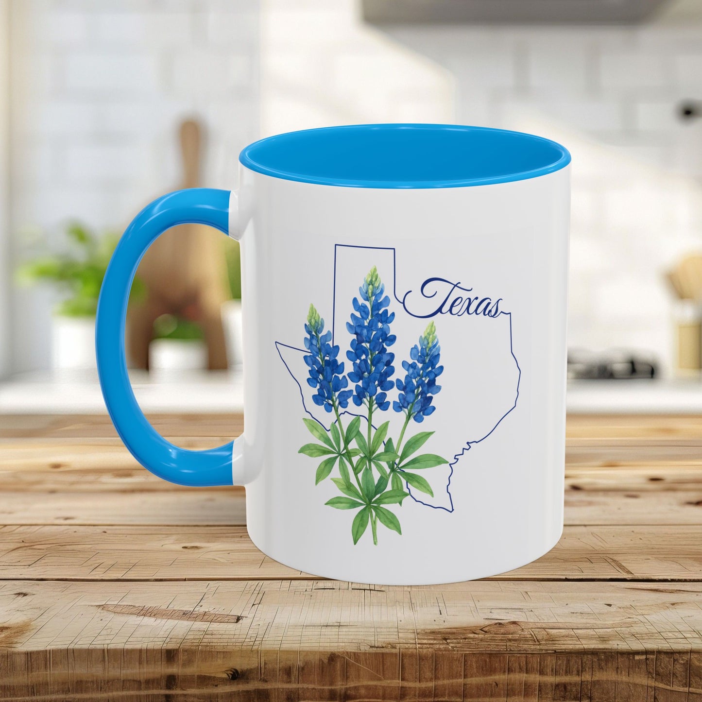 White ceramic mug with blue interior and handle, featuring a Texas outline and bluebonnet flowers.