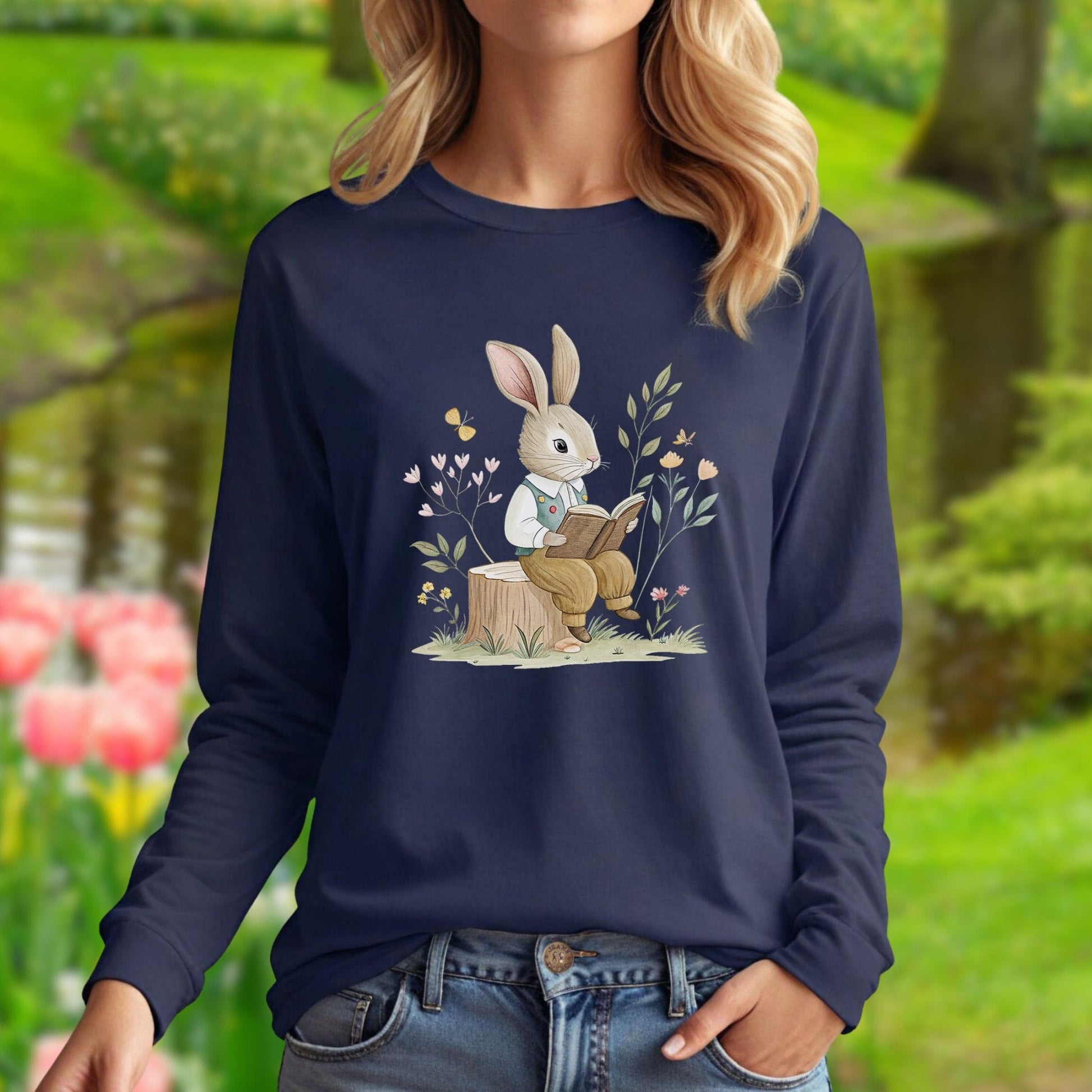 Navy long-sleeve tee with a whimsical rabbit reading on a tree stump, surrounded by spring botanicals.