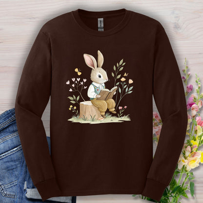 Dark Chocolate long-sleeve tee with a bookish spring bunny reading on a tree stump, surrounded by flowers.