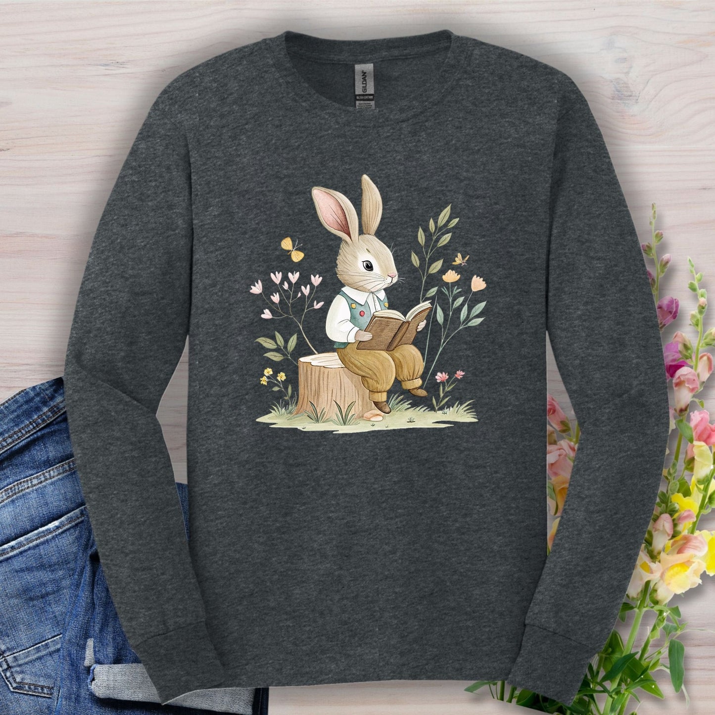 Dark Heather long sleeve tee with a whimsical bunny reading on a stump, surrounded by spring flowers.