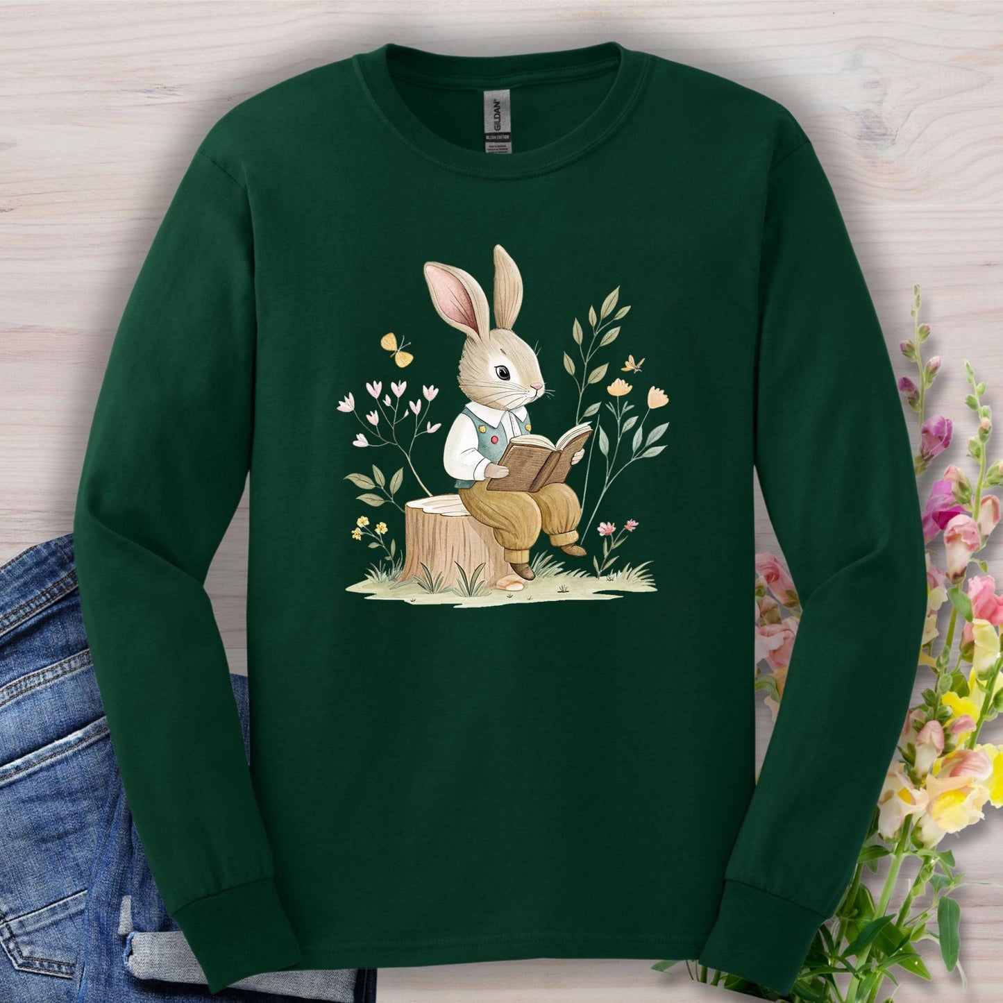 Forest Green long sleeve tee with a whimsical bunny reading on a tree stump, surrounded by spring botanicals.