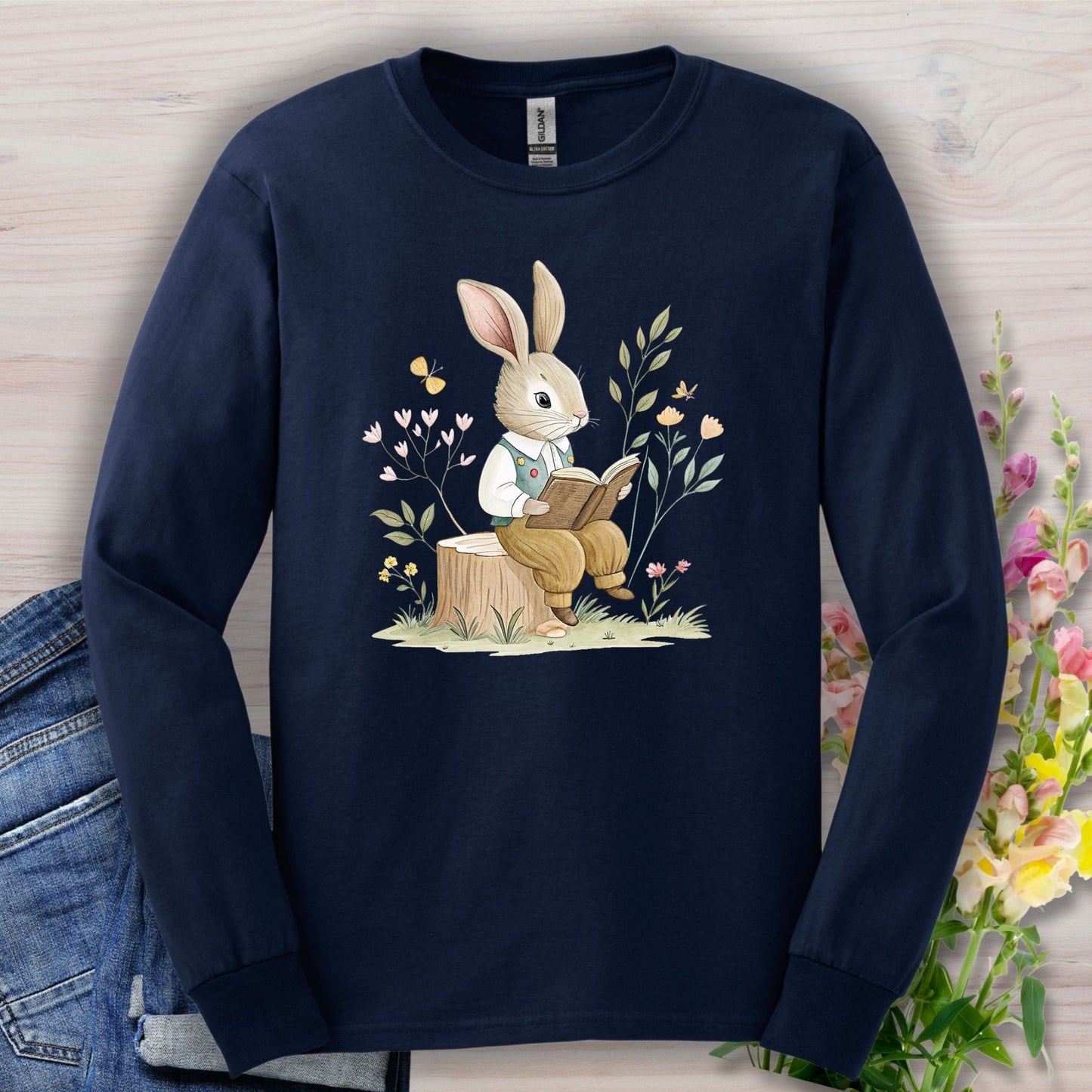 Navy long-sleeve tee with a bookish rabbit on a tree stump, surrounded by botanical elements.