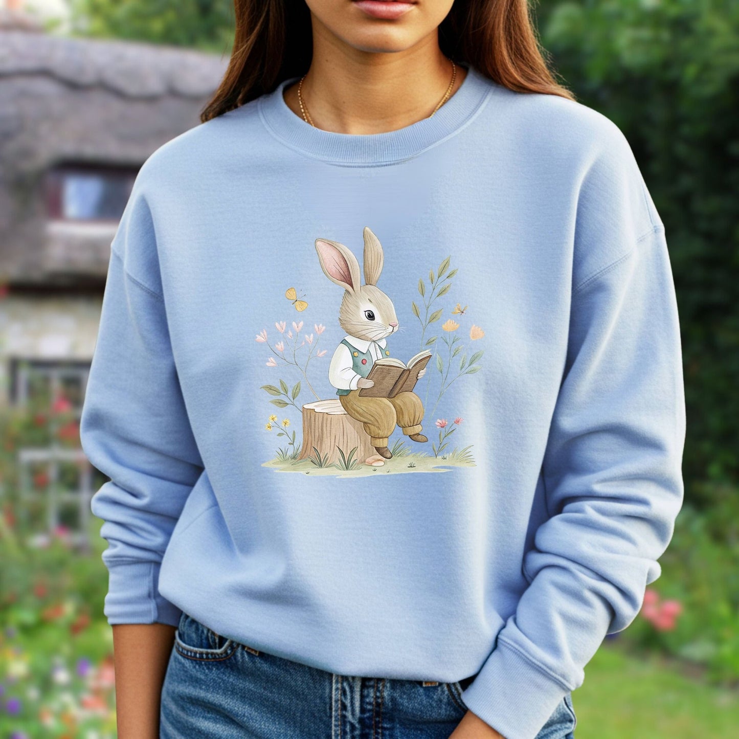 Light blue sweatshirt with a charming bunny in a waistcoat reading on a tree stump, surrounded by flowers.