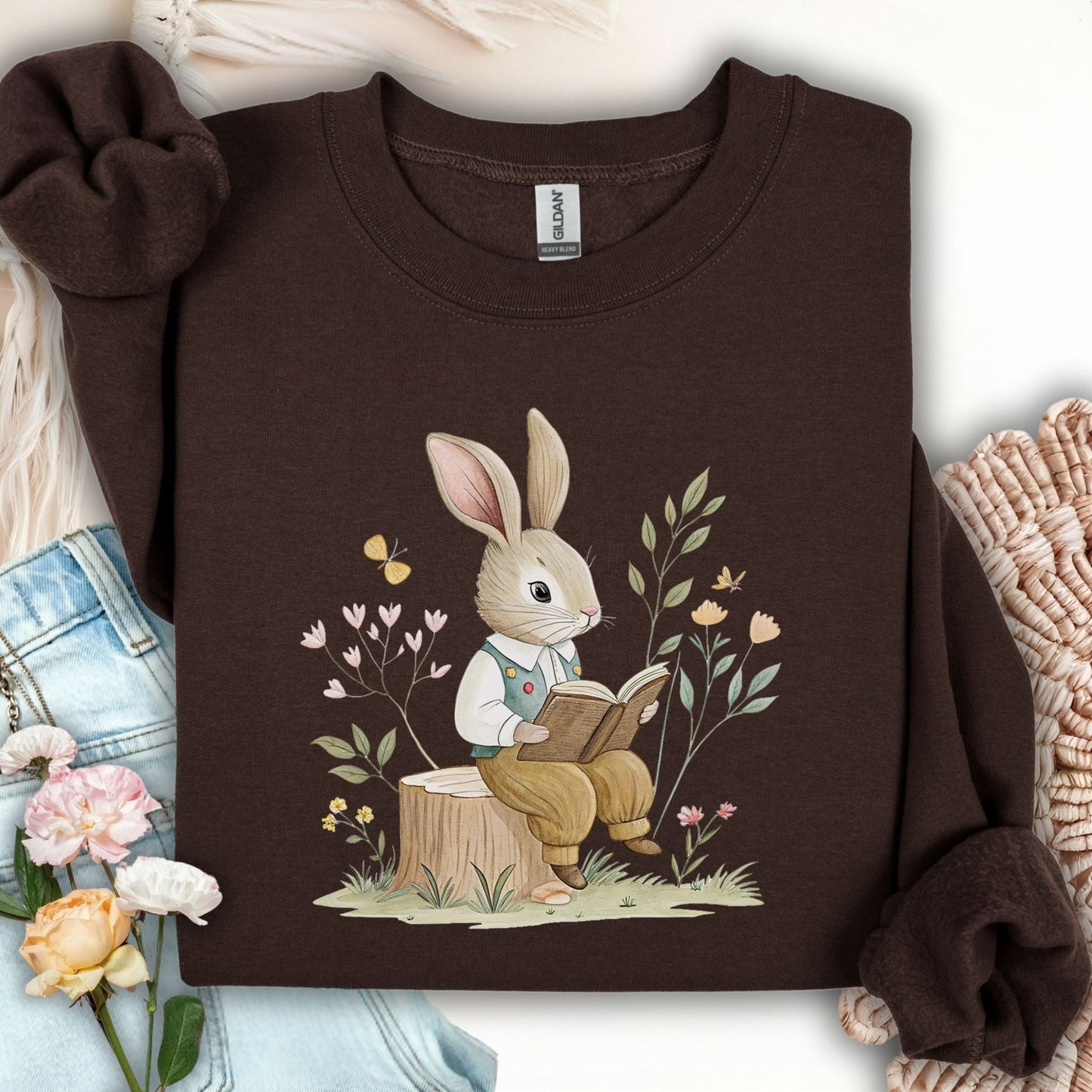 Dark Chocolate sweatshirt with a bookish bunny in a waistcoat reading on a tree stump, surrounded by spring flowers.