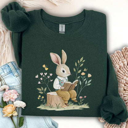 Forest Green sweatshirt with a bookish bunny in a waistcoat reading on a tree stump, surrounded by flowers and butterflies.