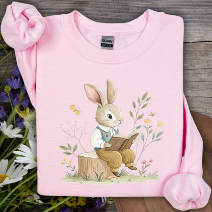 Light pink Gildan sweatshirt with a charming bunny reading a book in a whimsical garden illustration.