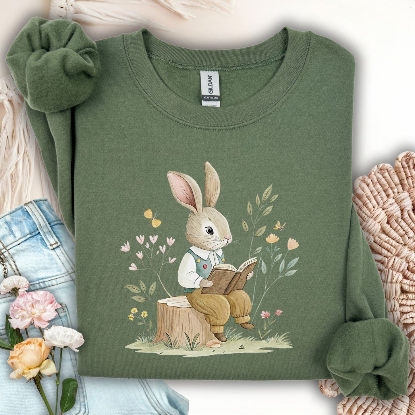 Military Green sweatshirt with a reading bunny in a waistcoat on a tree stump, surrounded by flowers and butterflies.