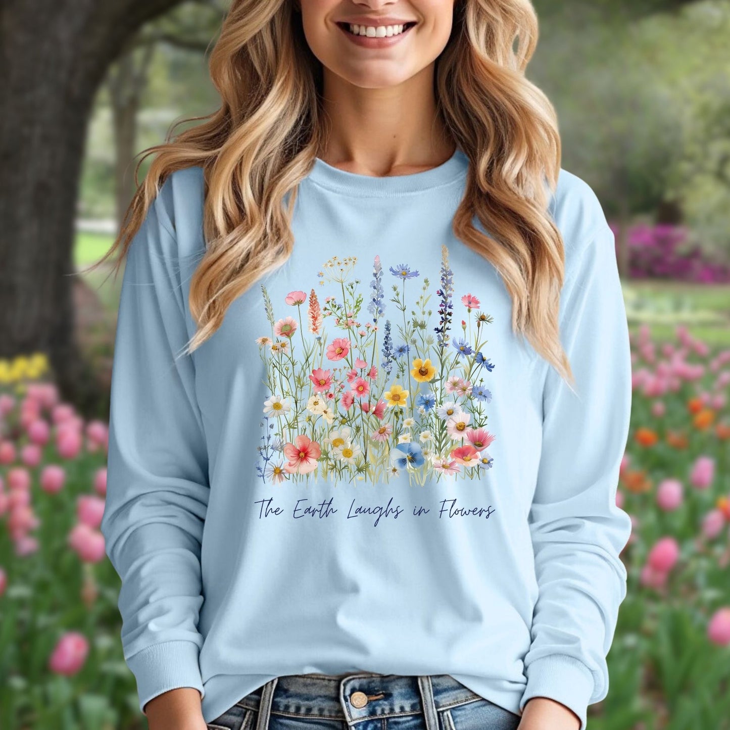 Light blue long-sleeve tee with watercolor wildflowers and "The Earth Laughs in Flowers" text.