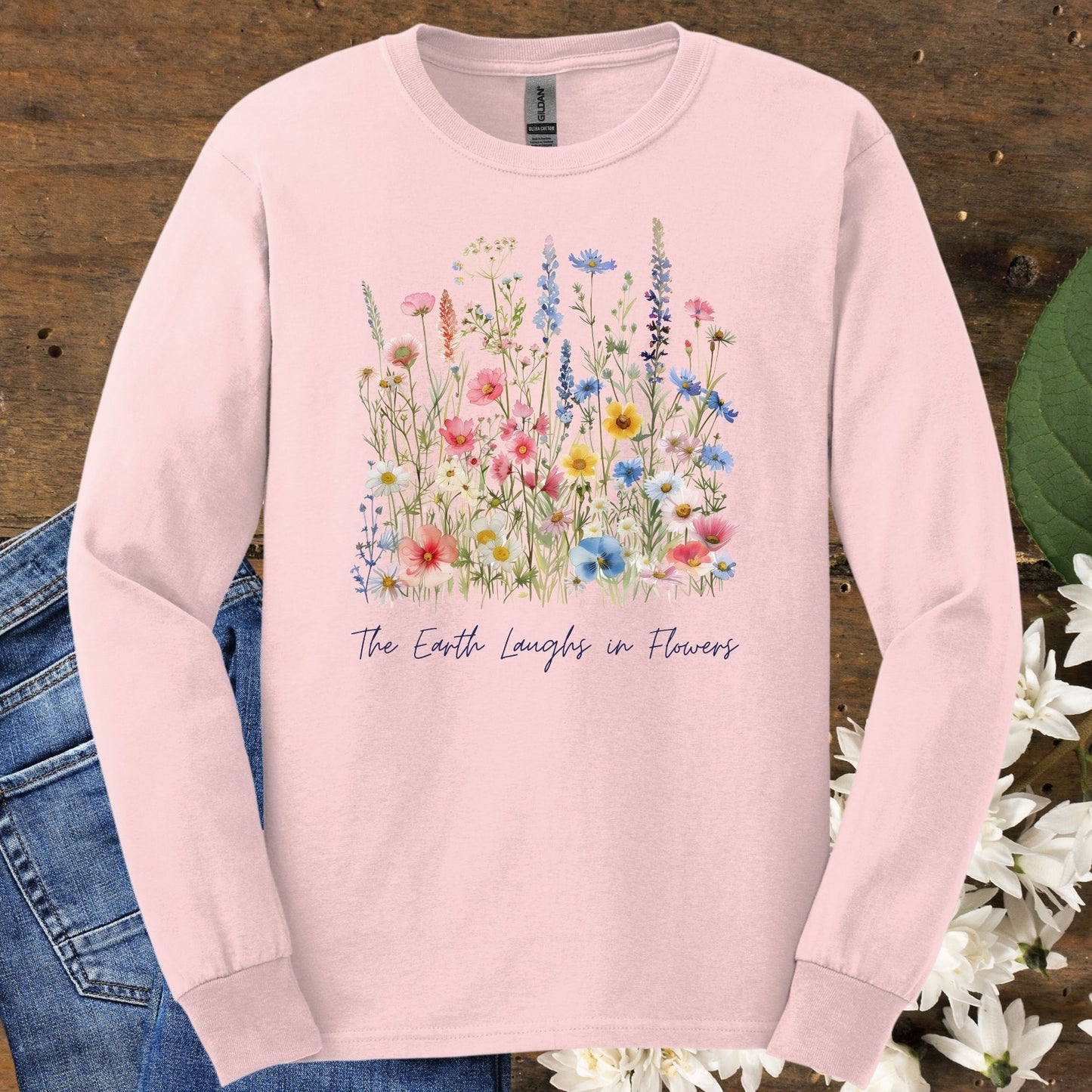 Light pink long-sleeve cotton tee with watercolor wildflowers and "The Earth Laughs in Flowers" text.