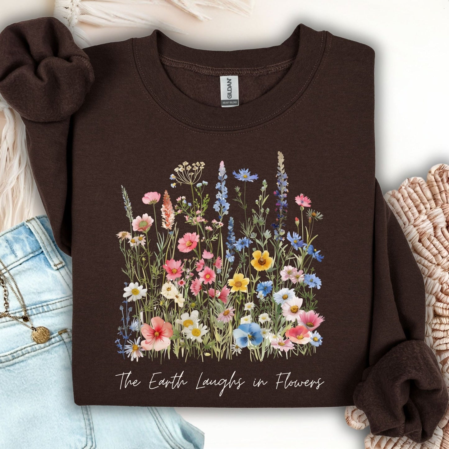 Dark chocolate crewneck sweatshirt with a colorful wildflower bouquet and "The Earth Laughs in Flowers" text.