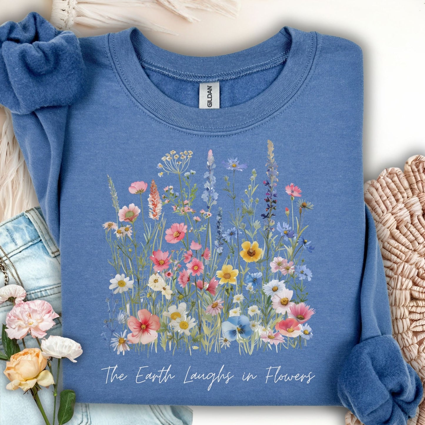 Indigo blue crewneck sweatshirt with a colorful wildflower bouquet and "The Earth Laughs in Flowers" text.