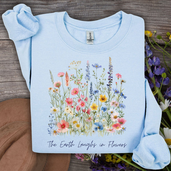Light blue crewneck sweatshirt with a colorful wildflower bouquet print and "The Earth Laughs in Flowers" text.