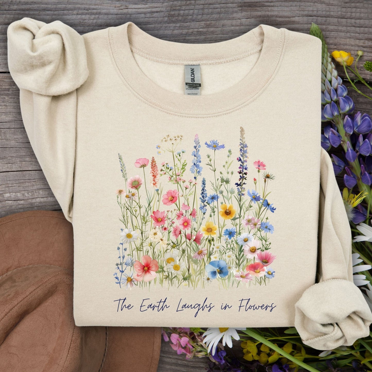 Sand unisex crewneck sweatshirt with a colorful wildflower bouquet and "The Earth Laughs in Flowers" text.