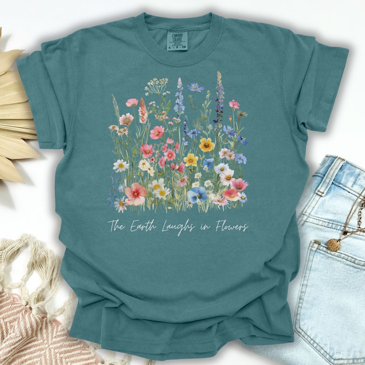 Blue Spruce garment-dyed cotton t-shirt with painterly wildflowers and "The Earth Laughs in Flowers" text.