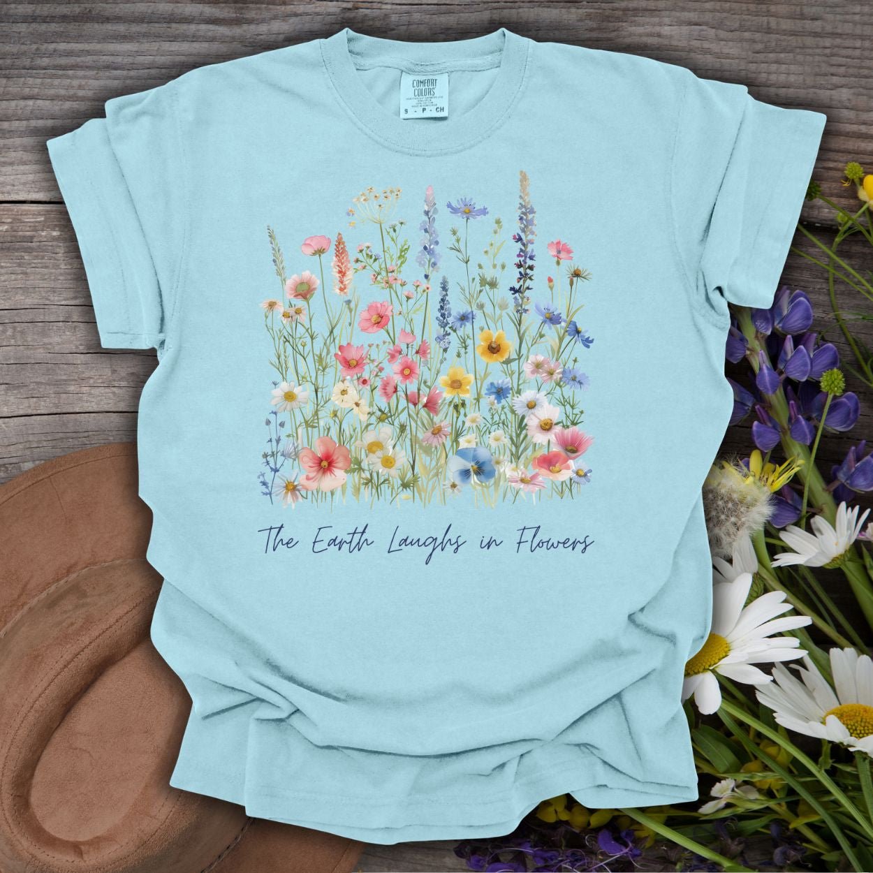 Chambray blue garment-dyed t-shirt with painterly wildflowers and "The Earth Laughs in Flowers" text.