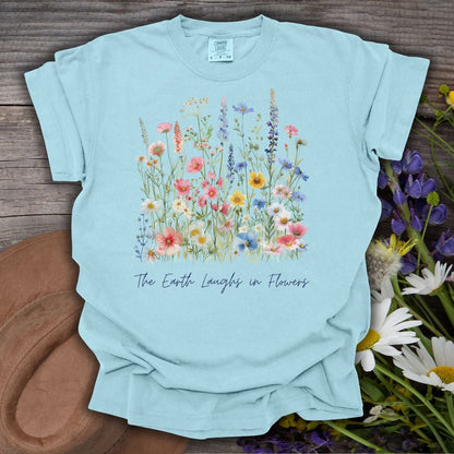 Chambray blue garment-dyed t-shirt with painterly wildflowers and "The Earth Laughs in Flowers" text.