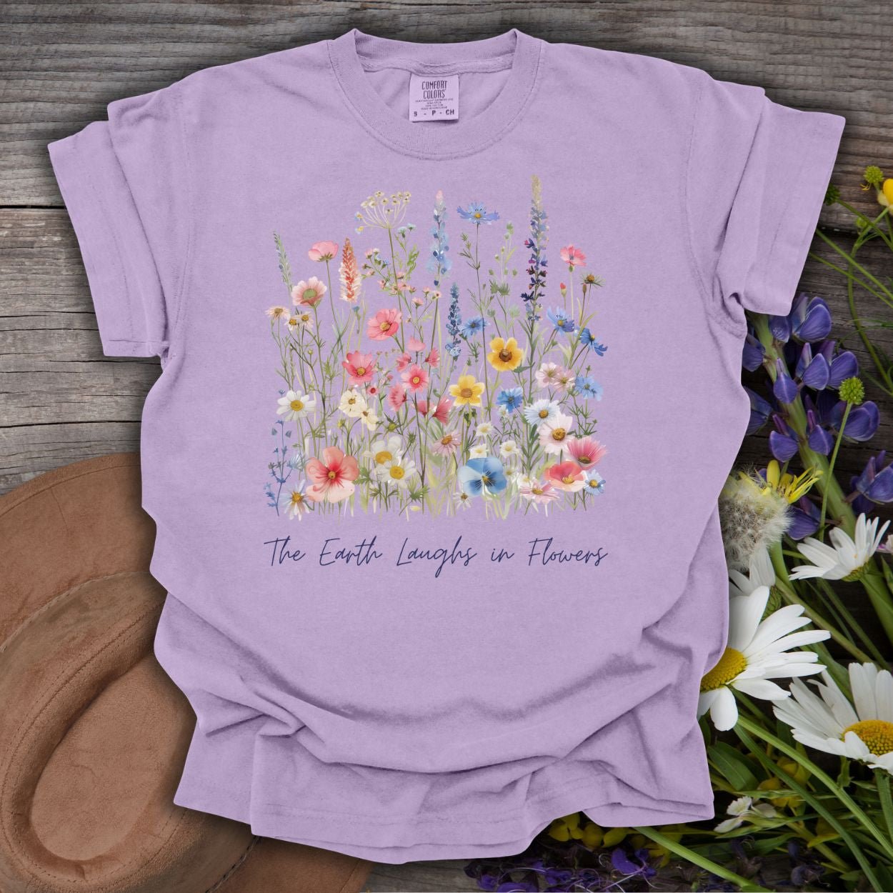 Orchid garment-dyed cotton t-shirt with painterly wildflowers and "The Earth Laughs in Flowers" text.