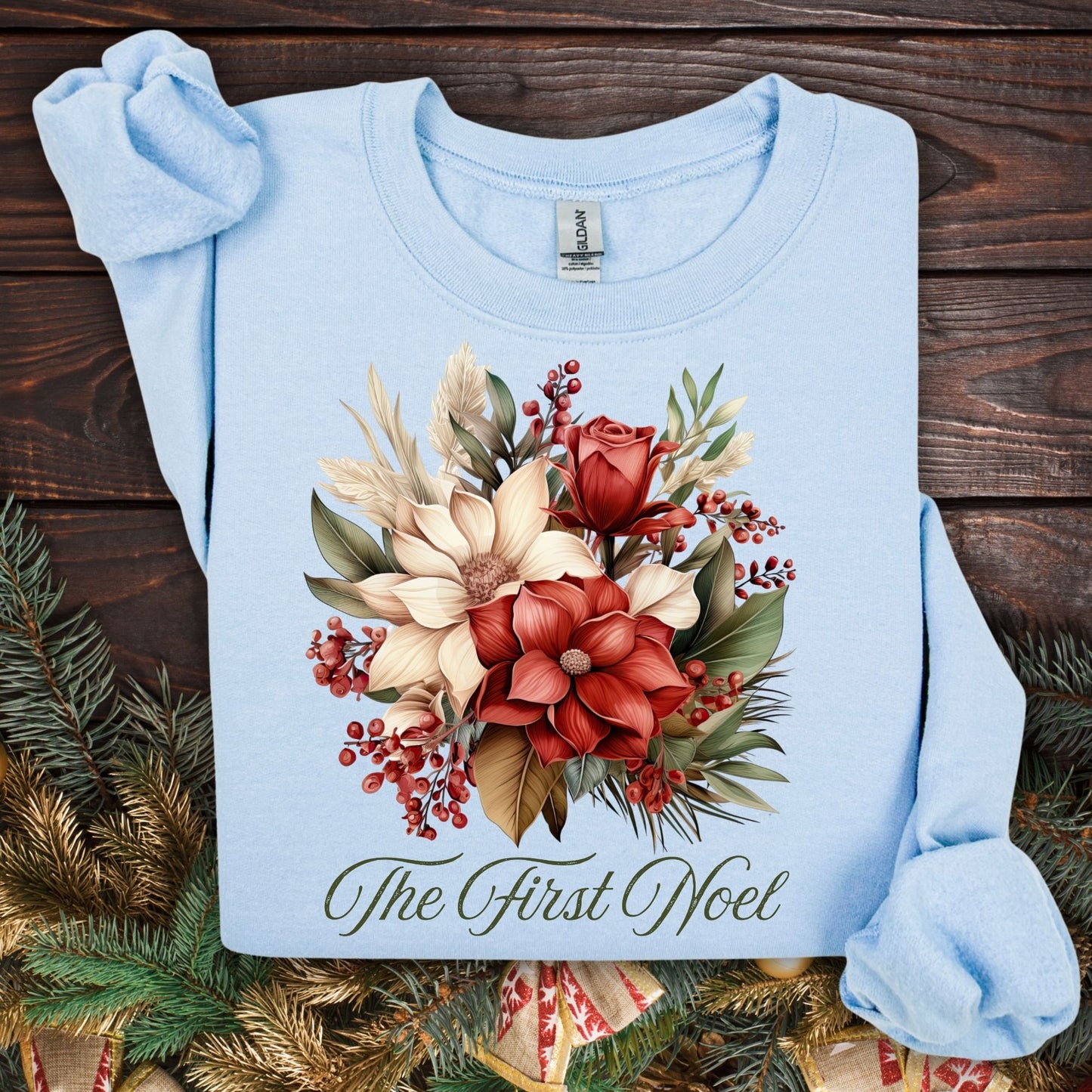 Light blue Gildan sweatshirt with vintage poinsettia, rose, and foliage bouquet, "The First Noel" text.