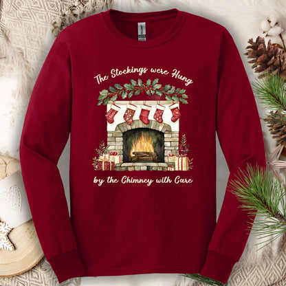Cardinal Red long sleeve tee with watercolor fireplace, red stockings, and "The Stockings Were Hung" text.