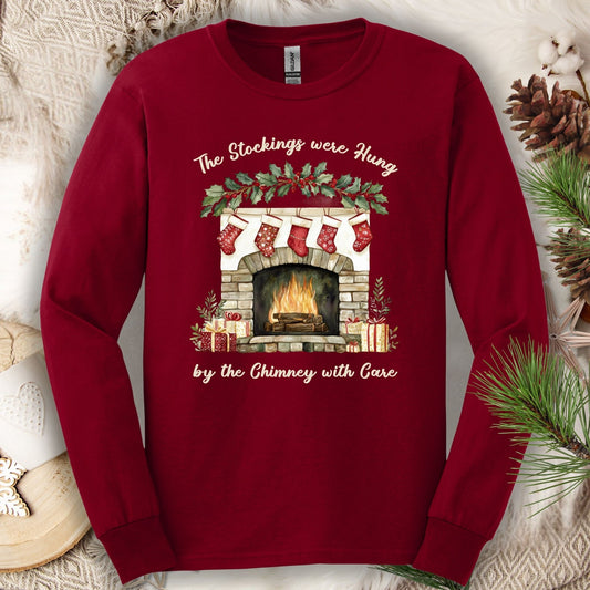 Cardinal Red long sleeve tee with watercolor fireplace, red stockings, and "The Stockings Were Hung" text.