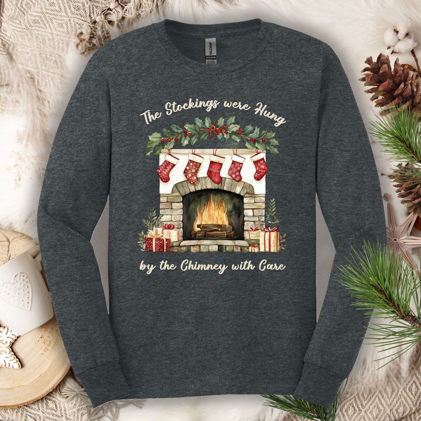Dark Heather long sleeve tee with a watercolor fireplace, red stockings, and "The Stockings were Hung" text.