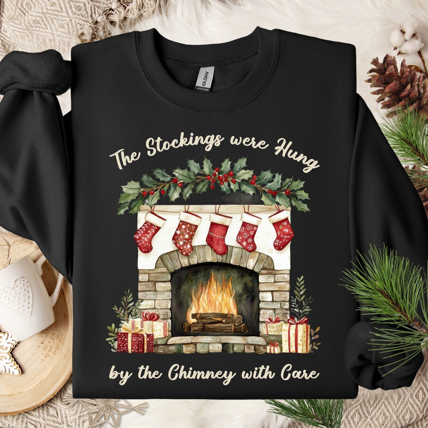 Black Gildan crewneck sweatshirt with a watercolor Christmas fireplace, stockings, and "The Stockings were Hung" text.