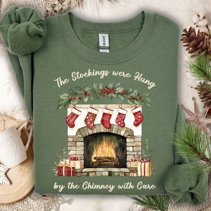 Military Green Gildan crewneck sweatshirt with "The Stockings were Hung by the Chimney with Care" text and fireplace watercolor design.