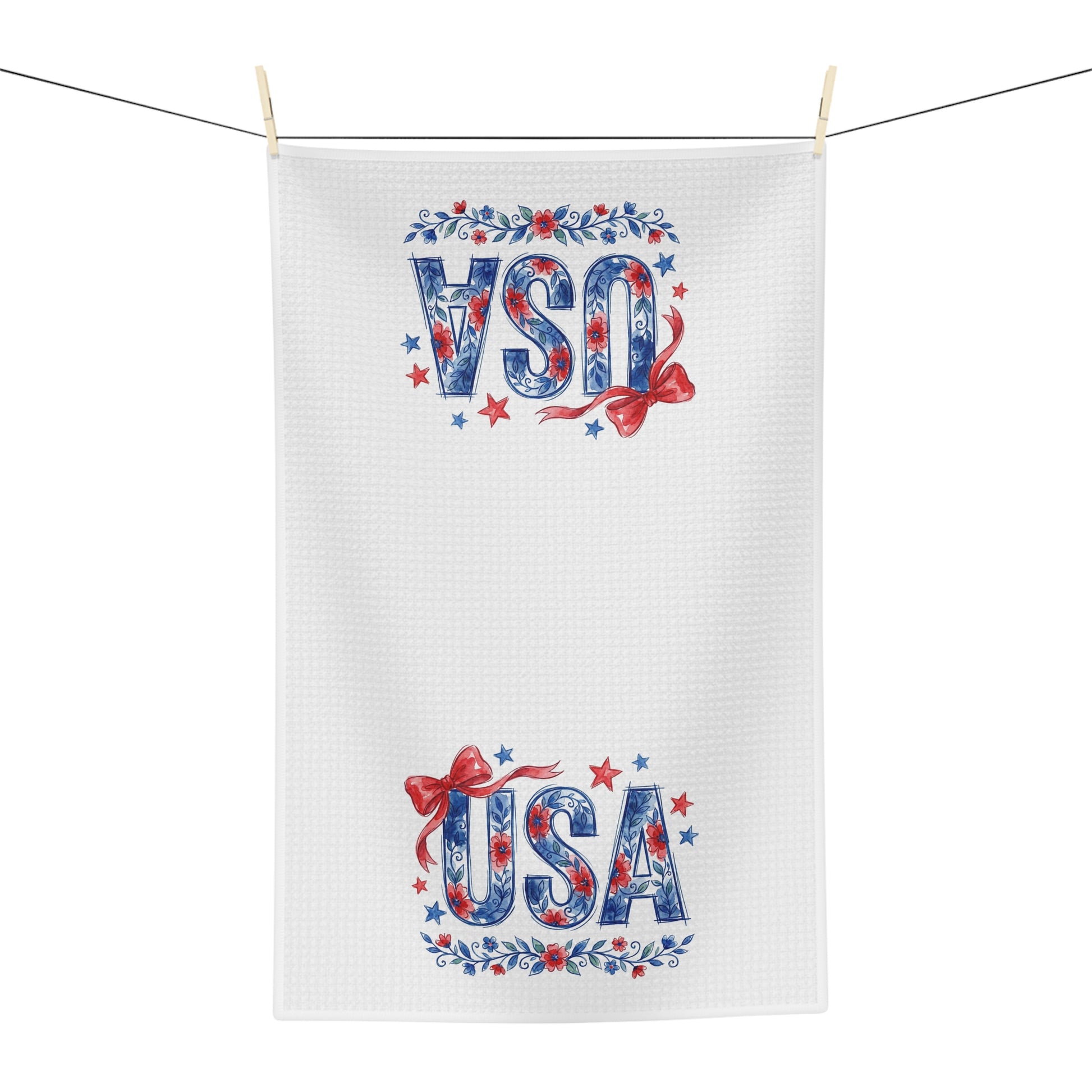White microfiber tea towel with red, white, and blue USA floral bows and stars design, hanging on a line.