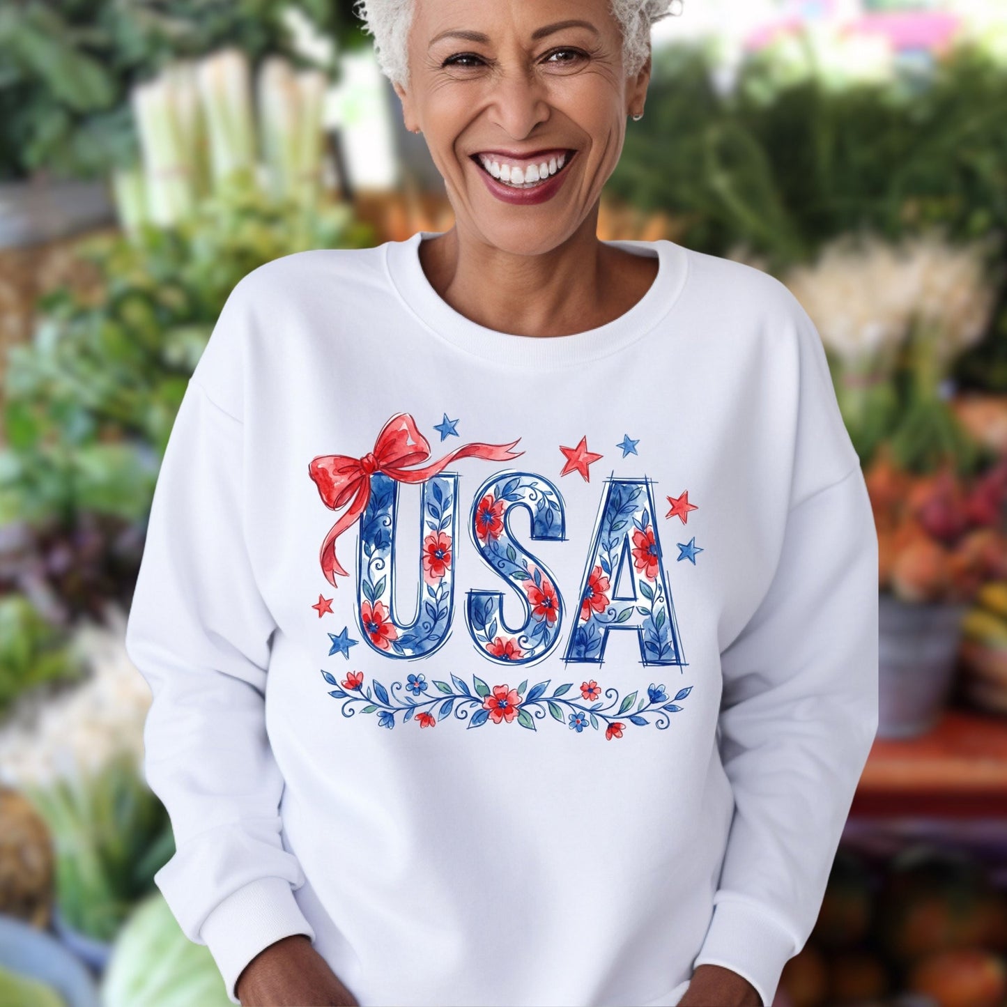 Smiling woman in a white USA Patriotic Floral Sweatshirt with blue florals, red stars, and a ribbon.