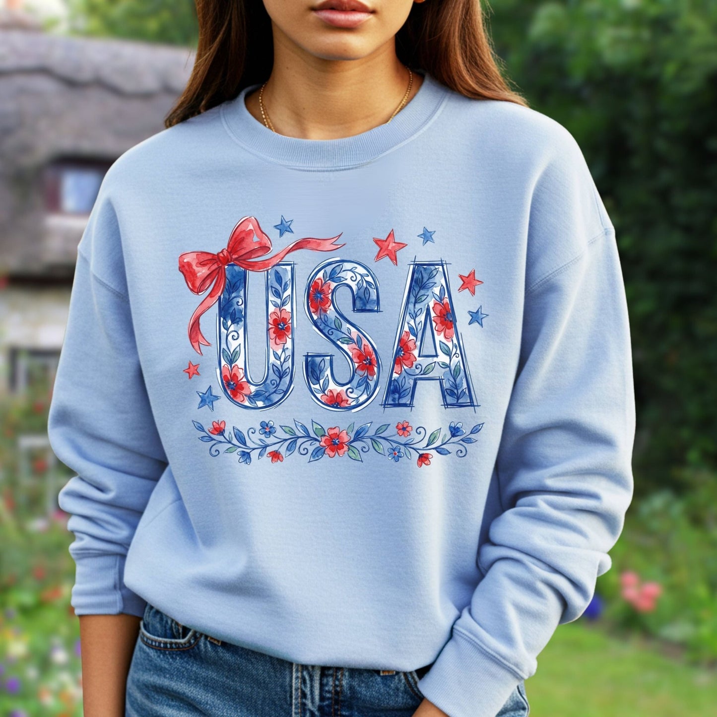 Light blue unisex sweatshirt with "USA" in blue floral print, red bow, and stars.