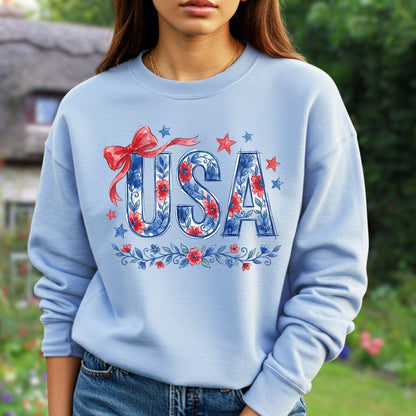 Light blue unisex sweatshirt with "USA" in blue floral print, red bow, and stars.