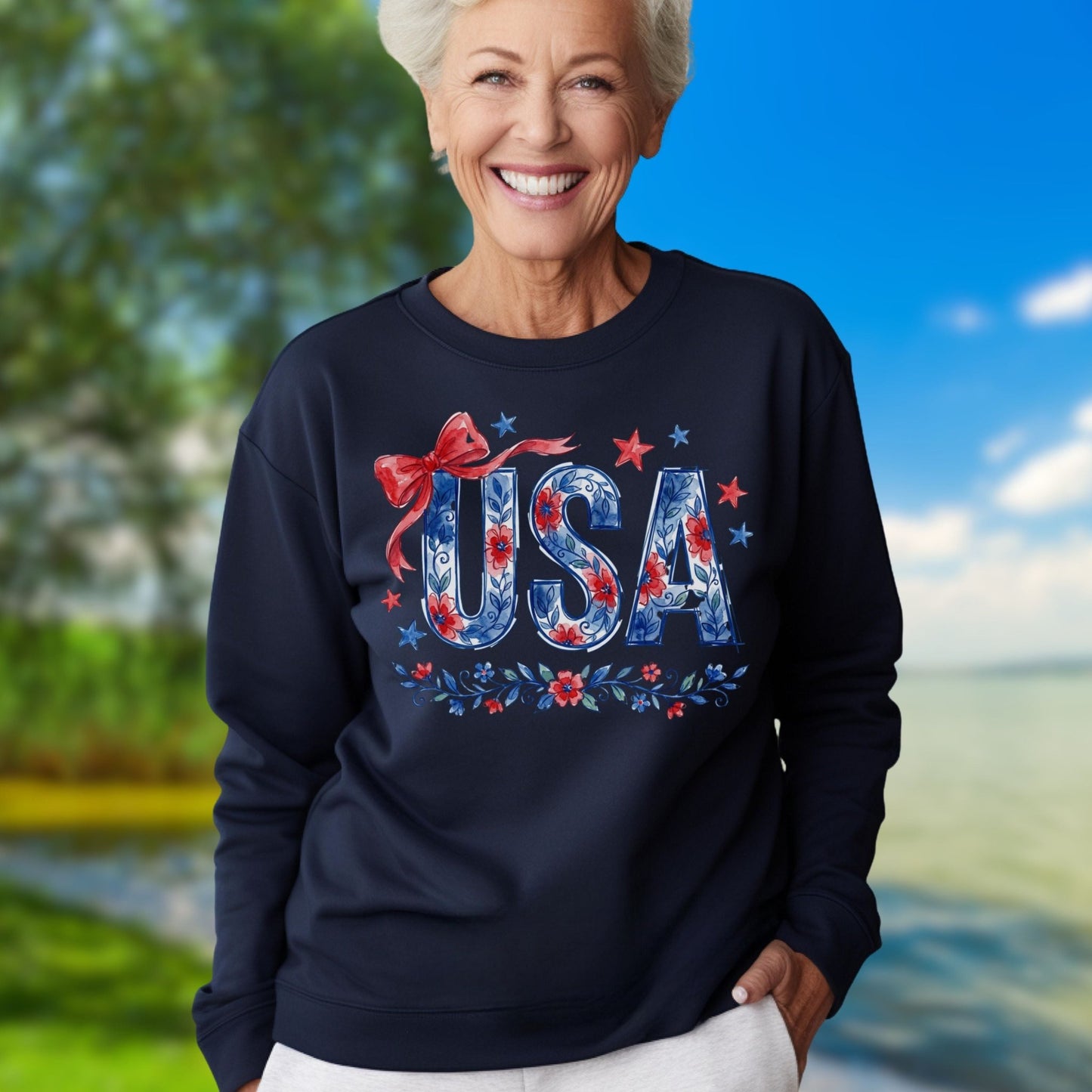 Smiling woman in a navy USA Patriotic Floral Sweatshirt with red bow and stars, outdoors.