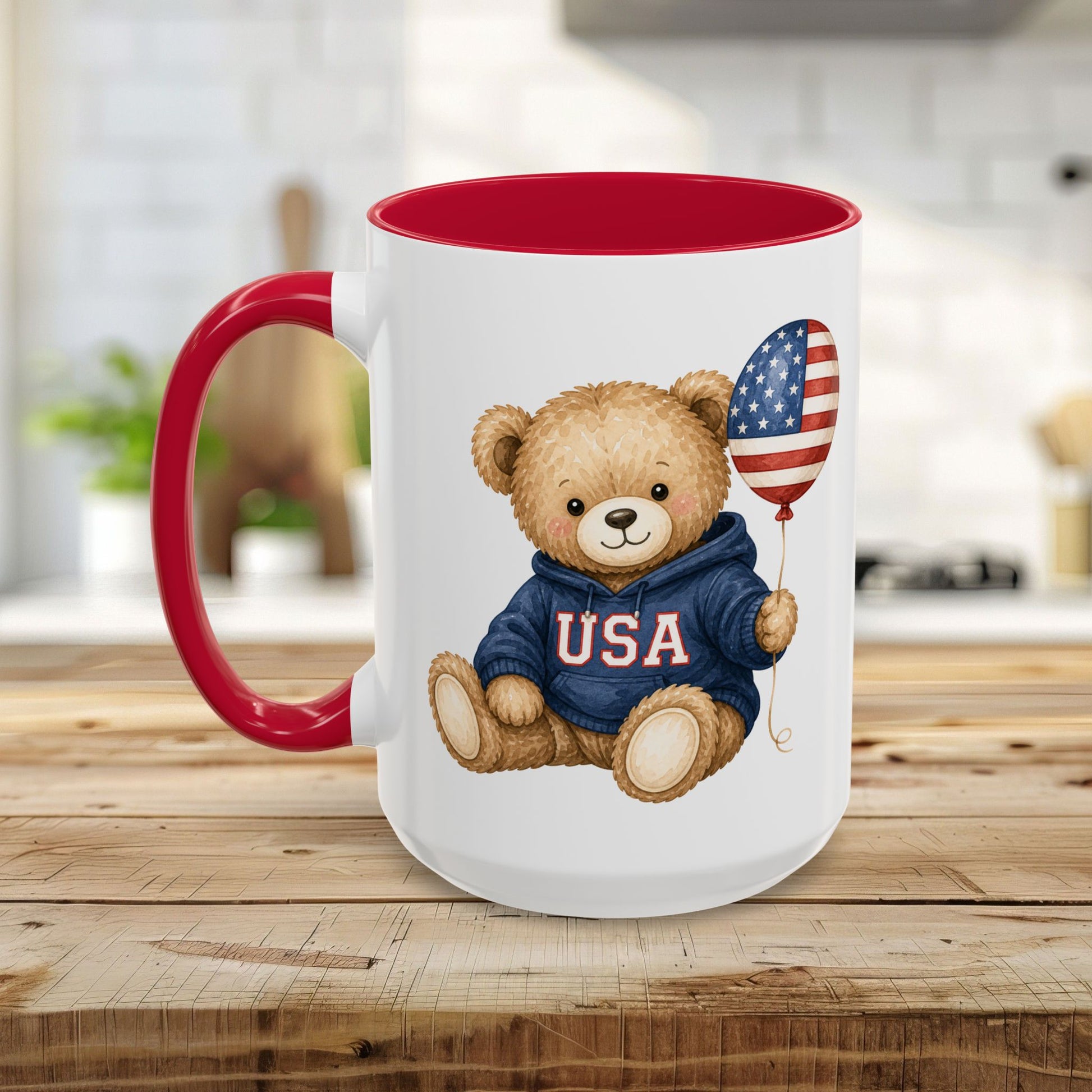 White ceramic mug with red handle and interior, featuring a teddy bear in a USA hoodie holding an American flag balloon.