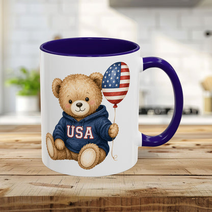 Blue 11oz ceramic mug with a teddy bear in a USA hoodie holding a flag balloon.