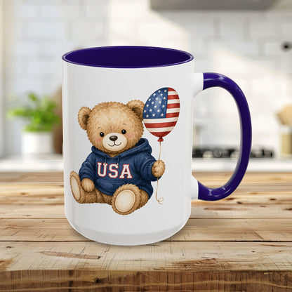 15oz ceramic mug with a cute teddy bear in a USA hoodie holding an American flag balloon, blue handle and interior.