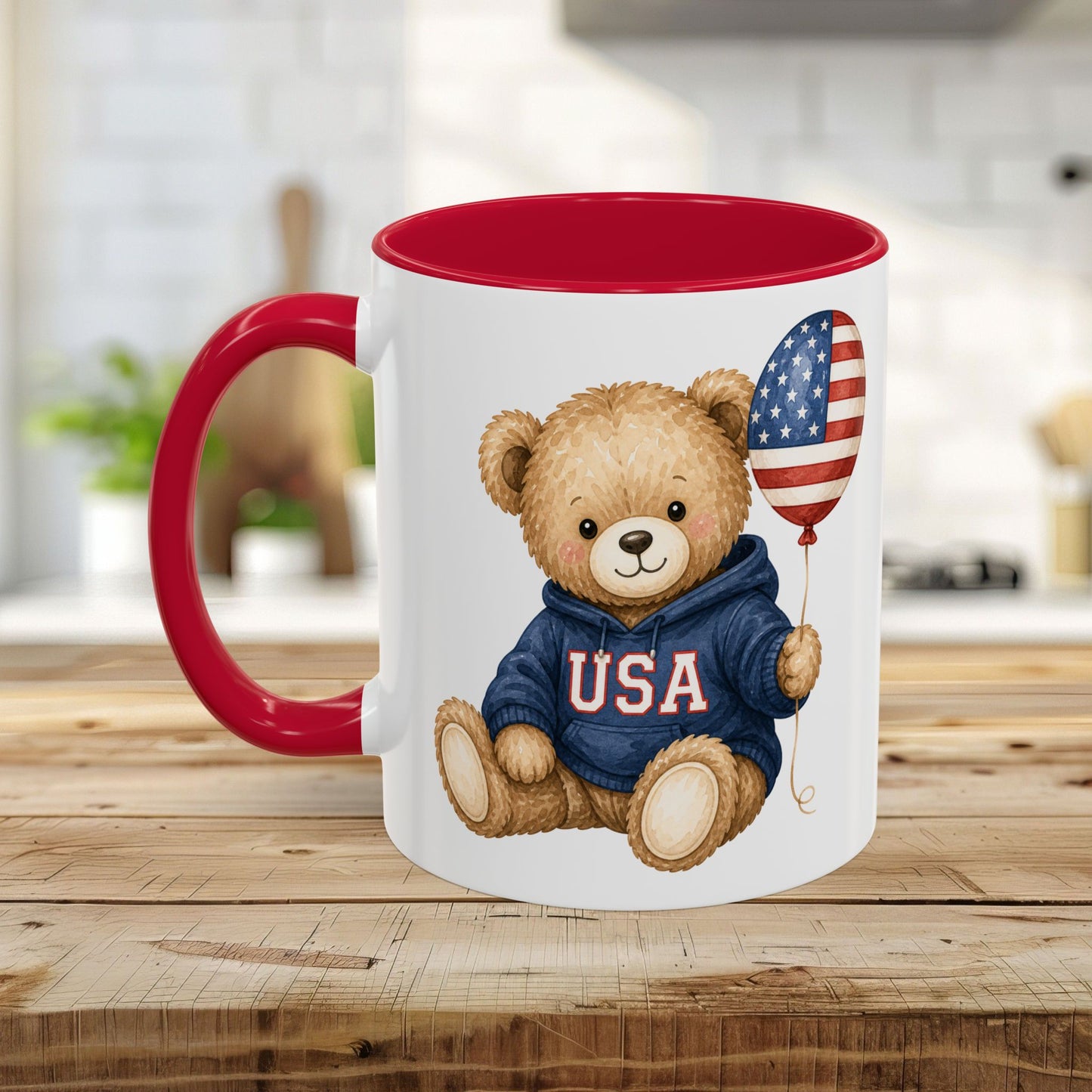 White ceramic mug with red handle and interior, featuring a teddy bear in a USA hoodie holding a flag balloon.